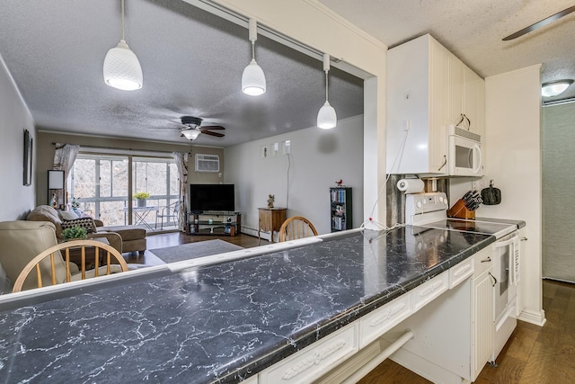 kitchen with dark countertops, white appliances, open floor plan, and decorative light fixtures