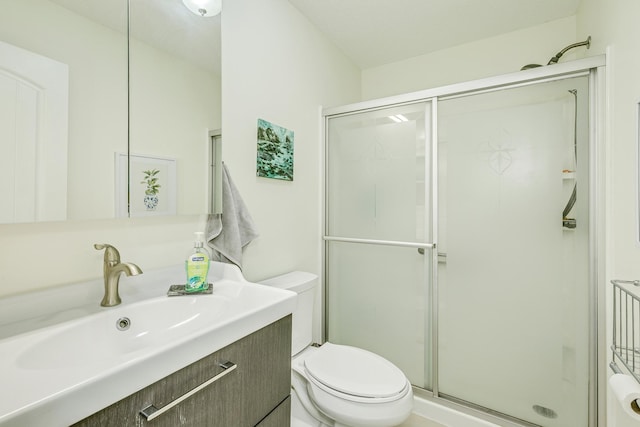 bathroom with vanity, a shower stall, and toilet