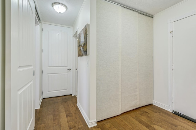 hallway featuring a textured ceiling, baseboards, and wood finished floors