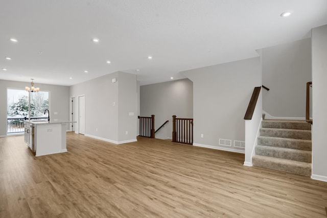 unfurnished living room featuring a notable chandelier, recessed lighting, a sink, visible vents, and light wood-type flooring