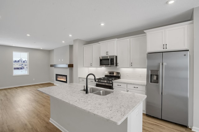 kitchen with stainless steel appliances, white cabinetry, a sink, and tasteful backsplash