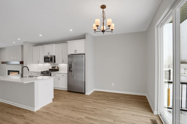 kitchen with visible vents, white cabinets, stainless steel appliances, light countertops, and light wood-style floors