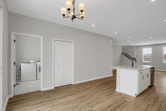 kitchen featuring light wood-type flooring, white cabinets, washer and clothes dryer, and a sink