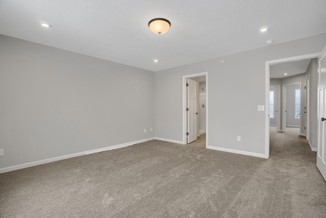 empty room with carpet floors, baseboards, a textured ceiling, and recessed lighting