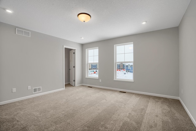 unfurnished room featuring carpet floors, visible vents, and baseboards