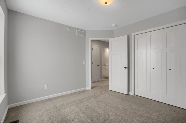 unfurnished bedroom with carpet, a closet, visible vents, and baseboards