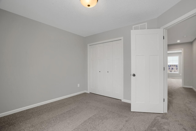 unfurnished bedroom featuring visible vents, baseboards, carpet, a textured ceiling, and a closet