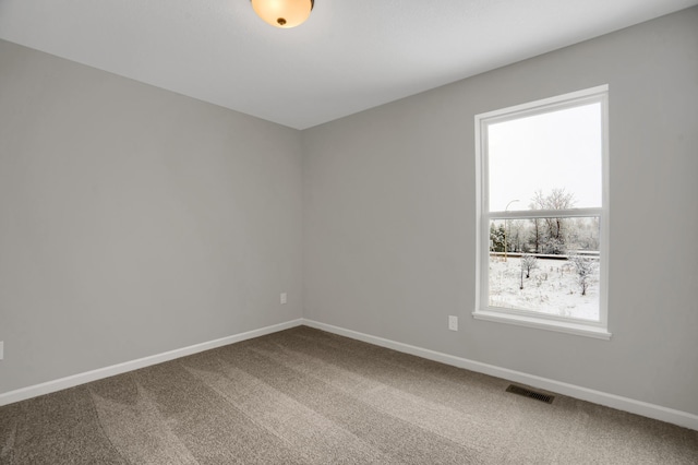 unfurnished room with carpet flooring, visible vents, and baseboards