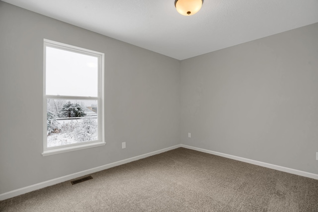 carpeted spare room featuring visible vents and baseboards