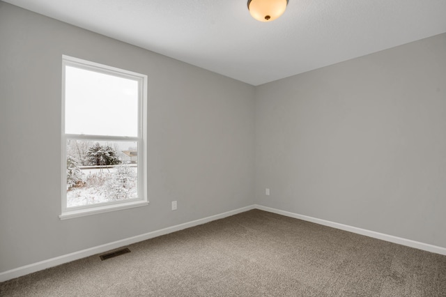 spare room with carpet floors, visible vents, and baseboards