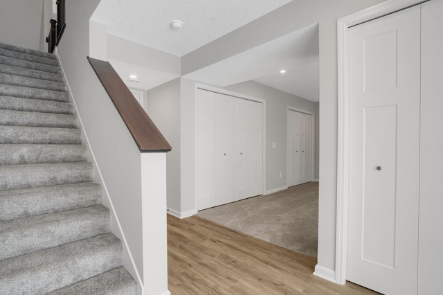 stairs featuring baseboards, wood finished floors, and recessed lighting