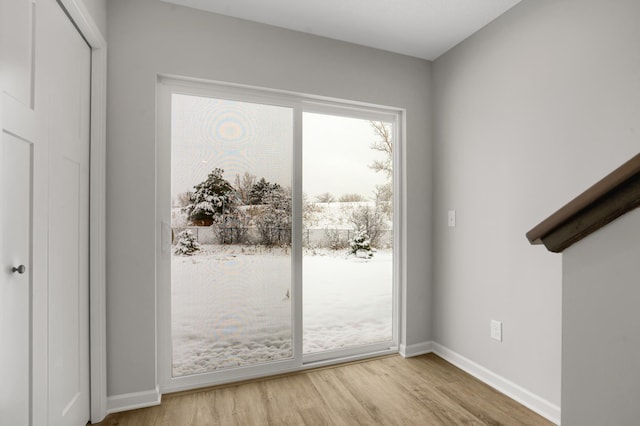 doorway to outside with wood finished floors and baseboards