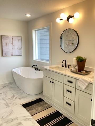 full bathroom with a freestanding tub, marble finish floor, and vanity