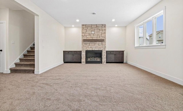 unfurnished living room featuring baseboards, carpet, and stairs