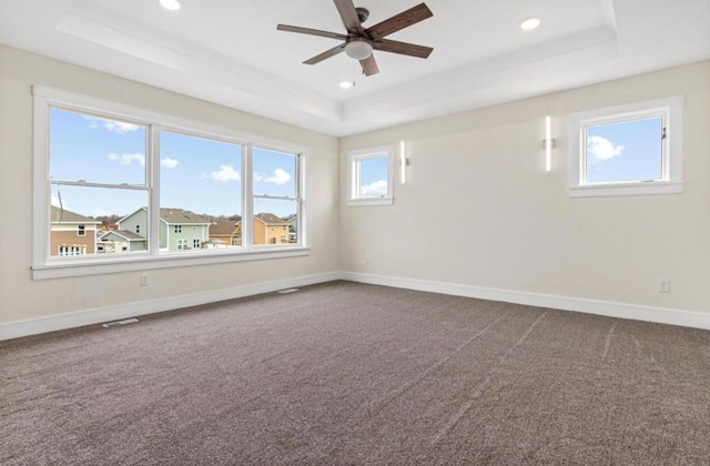 unfurnished room featuring dark carpet, baseboards, a raised ceiling, and a ceiling fan