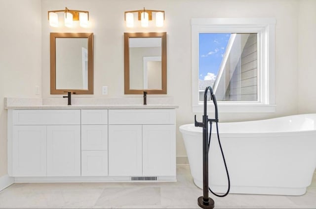 bathroom featuring double vanity, visible vents, a soaking tub, and a sink