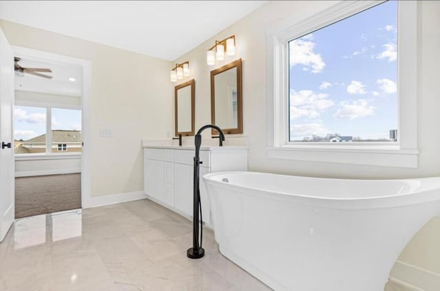 bathroom featuring vanity, ceiling fan, baseboards, and a freestanding bath