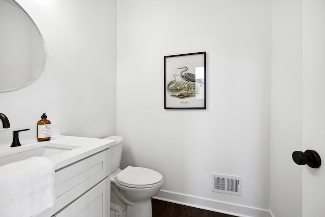 bathroom with visible vents, toilet, wood finished floors, baseboards, and vanity