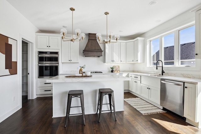 kitchen with a chandelier, a breakfast bar, custom exhaust hood, stainless steel appliances, and a sink