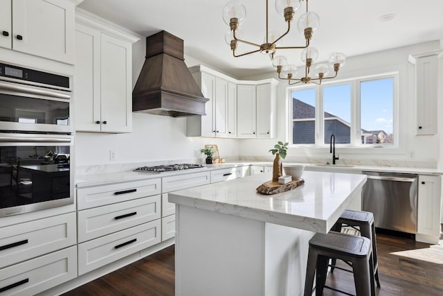 kitchen featuring dark wood finished floors, a sink, custom range hood, appliances with stainless steel finishes, and a chandelier