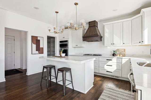 kitchen featuring light stone counters, premium range hood, a kitchen island, dark wood finished floors, and gas stovetop