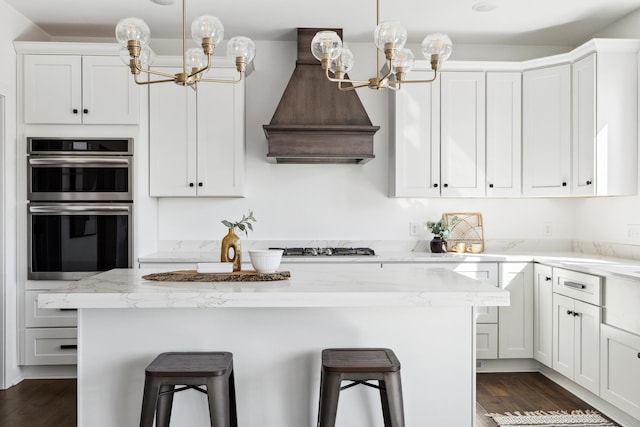 kitchen featuring a kitchen bar, custom exhaust hood, stainless steel double oven, and a chandelier