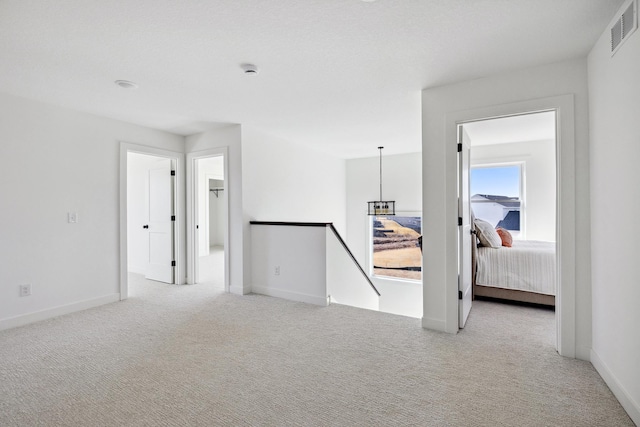 empty room featuring visible vents, light carpet, and baseboards