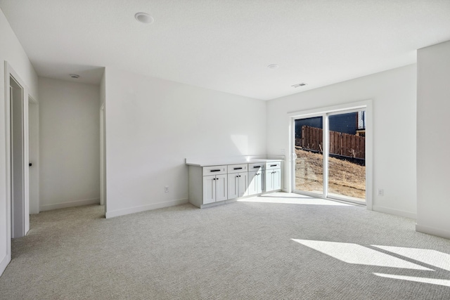 spare room with visible vents, light colored carpet, and baseboards