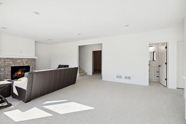 living area with visible vents, light colored carpet, a fireplace, and stairway