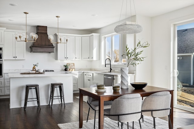 kitchen featuring dark wood-style floors, premium range hood, light countertops, stainless steel dishwasher, and a chandelier