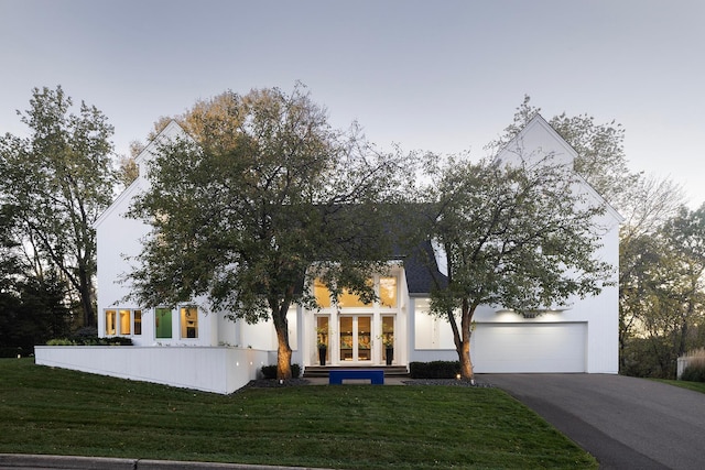 view of front of home with a garage, driveway, french doors, and a front lawn