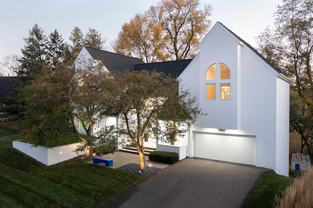 view of side of home with aphalt driveway, an attached garage, and fence