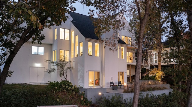 back of property with stucco siding, stairs, and a patio area