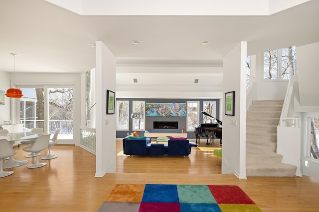 living area featuring light wood-type flooring, stairway, baseboards, and recessed lighting