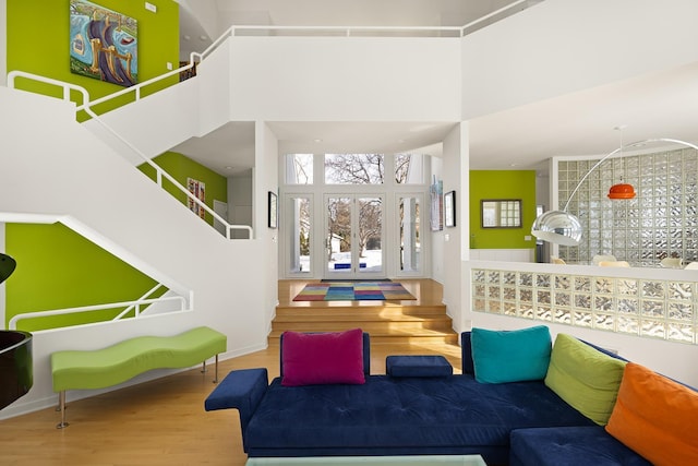 interior space featuring baseboards, a high ceiling, wood finished floors, and stairs