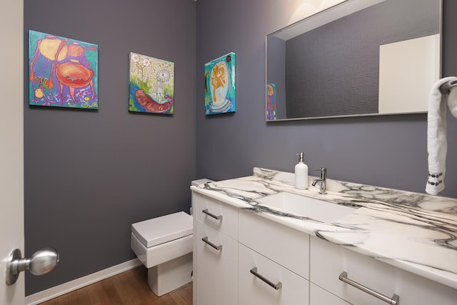 half bath featuring baseboards, toilet, wood finished floors, and vanity