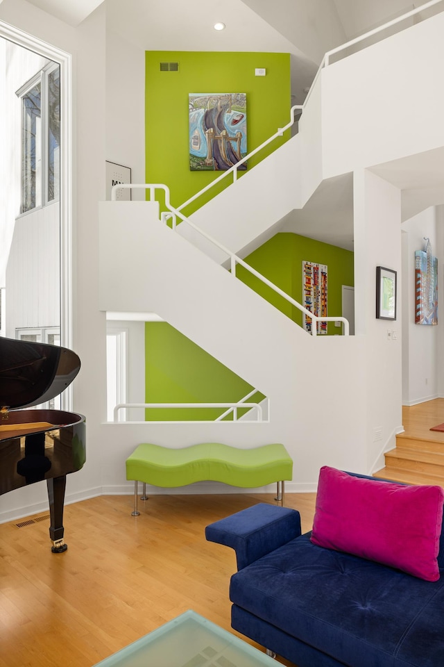 sitting room with visible vents, baseboards, a towering ceiling, and wood finished floors