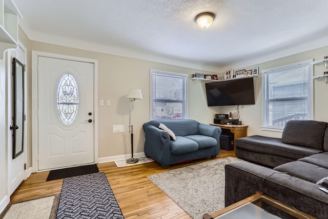 living room featuring a textured ceiling, baseboards, and wood finished floors