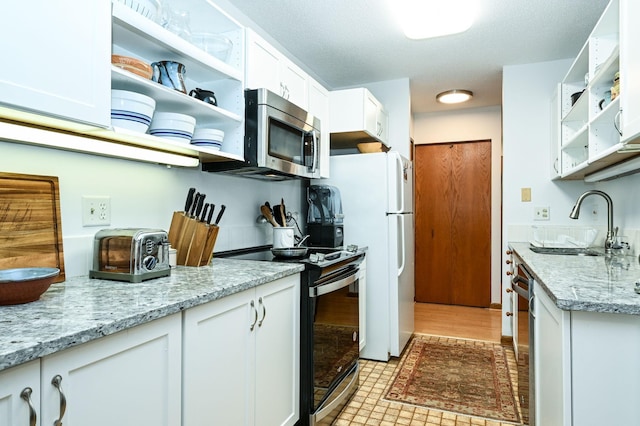 kitchen featuring open shelves, white cabinetry, stainless steel appliances, and a sink