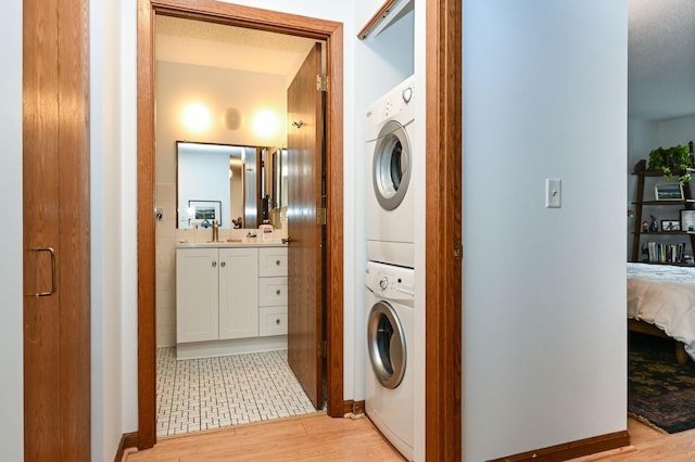 washroom featuring stacked washing maching and dryer, laundry area, and light wood finished floors