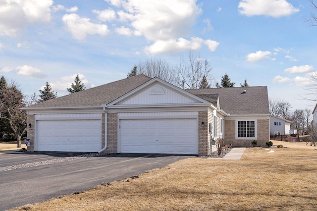 ranch-style home featuring brick siding, driveway, a shingled roof, and a front yard