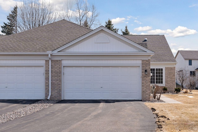 view of front of home featuring brick siding, an attached garage, aphalt driveway, and roof with shingles