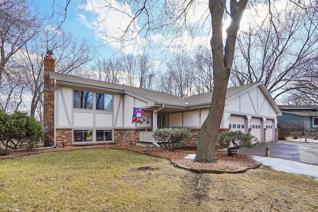 tudor-style house with driveway, a garage, brick siding, a chimney, and stucco siding