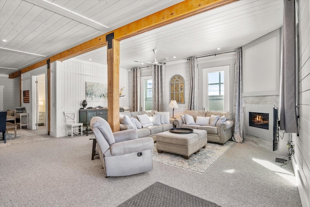 living area with wooden ceiling, carpet flooring, beamed ceiling, and a glass covered fireplace