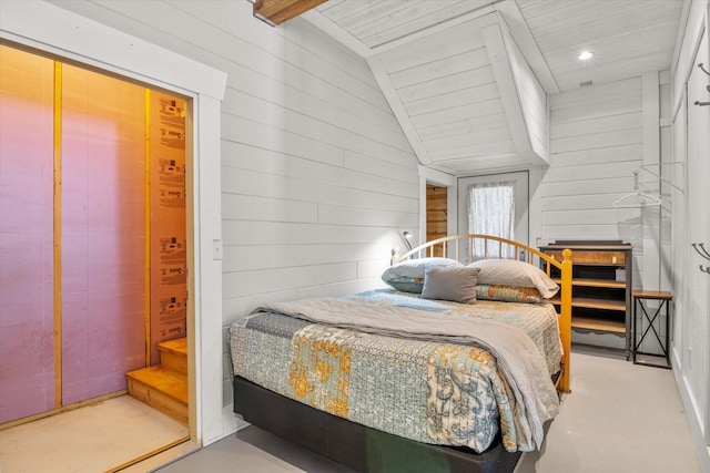 bedroom featuring vaulted ceiling and wood walls