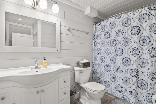 full bath with a shower with curtain, wood walls, vanity, and toilet