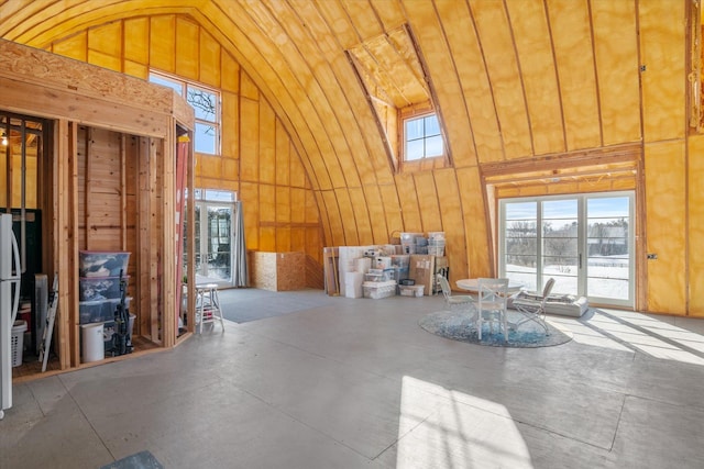 miscellaneous room with concrete flooring and high vaulted ceiling