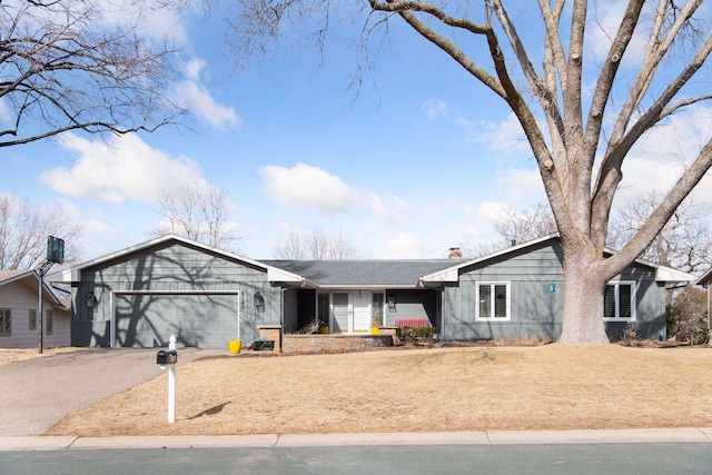 view of front of property featuring a garage, aphalt driveway, and a chimney