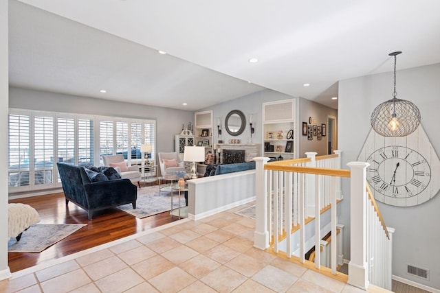 living room featuring visible vents, built in features, wood finished floors, a fireplace, and recessed lighting