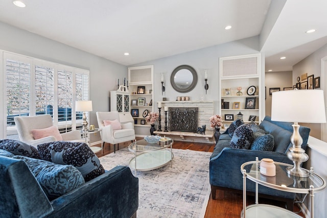 living area featuring recessed lighting, vaulted ceiling, a stone fireplace, and wood finished floors